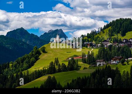 Häuser und Kirche des Dorfes Colle Santa Lucia, umgeben von grünen Weiden und Bäumen. Stockfoto