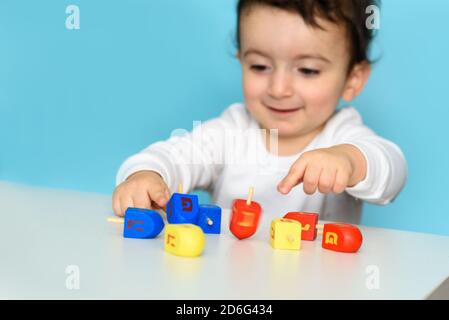 Kleine jüdische Junge spielt mit bunten Holz Dreidel. Selektiver Fokus auf Bewegung. Stockfoto