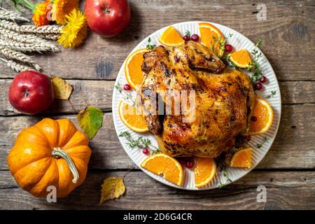 Gebackenes Huhn für Thanksgiving Day. Gebratenes Hähnchen oder truthahn mit Zitrusfrüchten und Gewürzen für Feiern Danktag auf Holztisch. Festlicher Tisch Stockfoto