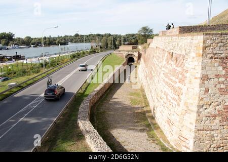 Belgrad, Serbien - 09. Oktober 2020: Menschen sitzen und gehen zu Fuß Weg der Festung Kalemegdan, Autos vorbei an der Straße und das Flusswasser Stockfoto