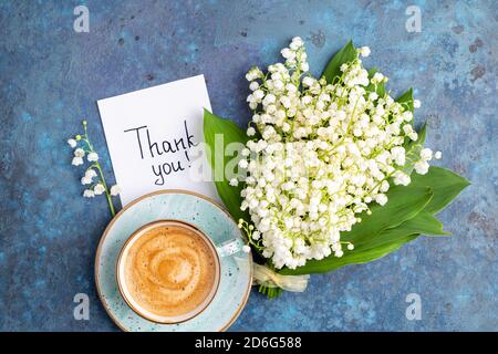 Anmerkungen Danke und Kaffeebecher mit Blumenstrauß Maiglöckchen auf blauem Hintergrund. Dankbarkeit, Kaffeetasse, Kundenservice, Dankeskarte Stockfoto