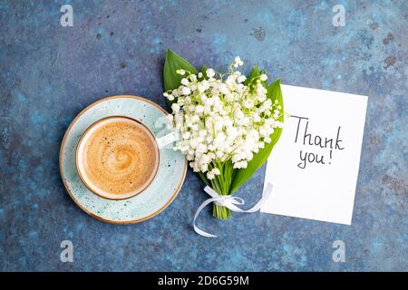 Anmerkungen Danke und Kaffeebecher mit Blumenstrauß Maiglöckchen auf blauem Hintergrund. Dankbarkeit, Kaffeetasse, Kundenservice, Dankeskarte Stockfoto