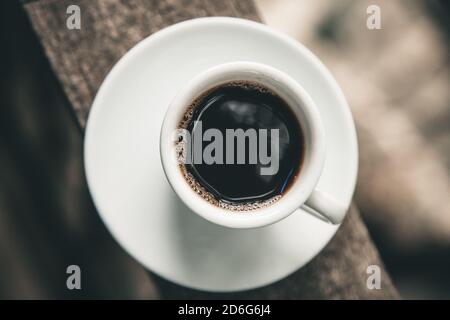 Schwarze Kaffeetasse auf dem Land Balkon Holzkante Draufsicht Stockfoto