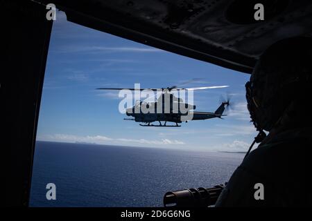 PHILIPPINISCHES MEER (Sept 18, 2020) EINE Marine mit Marine Medium Tiltrotor Squadron (VMM) 262 (verstärkt), 31. Marine Expeditionary Unit, blickt aus der Tür eines UH-1Y Huey Hubschraubers auf einen AH-1Z Cobra Angriffshubschrauber, während sie zu einer Reichweite fliegen. New Orleans, Teil der America Amphibious Ready Group, 31. MEU-Team, ist im 7. Einsatzbereich der US-Flotte tätig, um die Interoperabilität mit Verbündeten und Partnern zu verbessern und als einsatzbereite Einsatztruppe zur Verteidigung von Frieden und Stabilität in der Indo-Pazifik-Region zu dienen. (USA Marine Corps Foto von Sgt. Audrey M. C. Rampton) Stockfoto