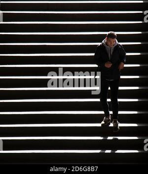 Belgrad, Serbien - 09. Oktober 2020: Junger Mann, der die öffentlichen Treppen der Stadt hinuntergeht, in hohem Kontrast Stockfoto