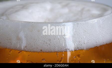 Oben auf dem Bierglas in Nahaufnahme mit all den winzigen Blasen und hellweißem Schaum. Bier und andere Getränke Konzeptfoto. Stockfoto