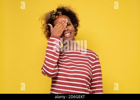 Junge afrikanische Frau schließt ein Auge mit lächelnder Hand Während des optischen Tests Stockfoto