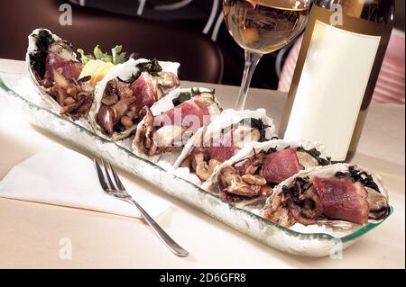 Austern mit Speck und Pilzen in feiner Speiseteller-Präsentation Stockfoto