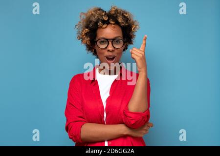 Hübsche afrikanische Frau mit einer großen Idee zeigt mit dem Finger nach oben. Stockfoto