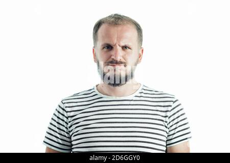 Verärgerter bärtiger Erwachsener in einem gestreiften T-Shirt. 30-35 Jahre alt. Isoliert auf Weiß. Stockfoto