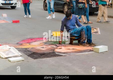 Große Nahaufnahme eines Straßenkünstlers in Florenz, Zeichnung mit Kreide auf Asphalt die berühmte Madonna della seggiola Gemälde von der italienischen... Stockfoto