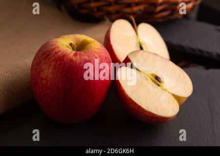 Zwei rote Äpfel auf einem Stück Schiefer in Eine Umgebung mit schwachem Licht Stockfoto