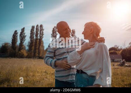 Glückliches Seniorenpaar Dating, Umarmung und küssen im Freien bei Sonnenuntergang Stockfoto