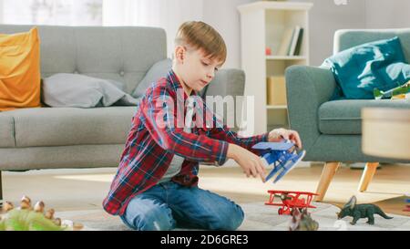 Zu Hause: Smart Little Boy spielt mit Spielzeug Flugzeug. Kleines Kind spielt auf einem Teppich im sonnigen Wohnzimmer. Stockfoto