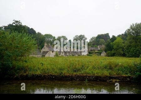 Bibury, Cotswolds, England - EIN Blick auf den Fluss und Arlington Row in Bibury an einem regnerischen Sommertag. Stockfoto