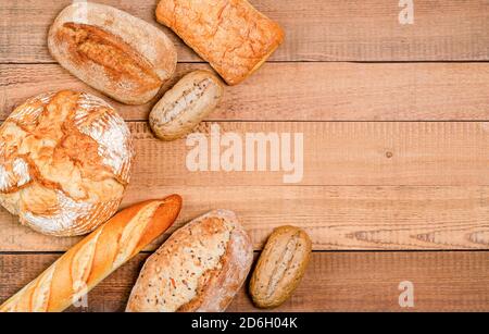 Bäckerei - verschiedene rustikale knusprige Brote und Brötchen auf Holzbrettern. Platz kopieren, flach legen, für Text platzieren. Blick von oben. Stockfoto