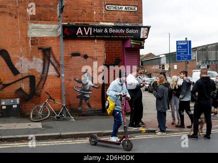 Nottingham, Nottinghamshire, Großbritannien. Oktober 2020. Ein Mann sucht sich ein Werk des Graffiti-Künstlers Banksy. Die Arbeit, außerhalb eines Schönheitssalons, zeigt ein Mädchen Hula-Hooping mit einem Fahrradreifen neben einem Fahrrad, das sein Hinterrad fehlt. Credit Darren Staples/Alamy Live News. Stockfoto