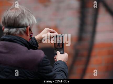 Nottingham, Nottinghamshire, Großbritannien. Oktober 2020. Ein Mann fotografiert ein Werk des Graffiti-Künstlers Banksy. Die Arbeit, außerhalb eines Schönheitssalons, zeigt ein Mädchen Hula-Hooping mit einem Fahrradreifen neben einem Fahrrad, das sein Hinterrad fehlt. Credit Darren Staples/Alamy Live News. Stockfoto