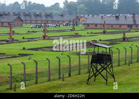 Ein Teil des Staatlichen Museums Auschwitz-Birkenau in Oswiecim in Polen, der den elektrischen Zaun und die Ziegelkamine der Häftlingsbaracken zeigt. Stockfoto