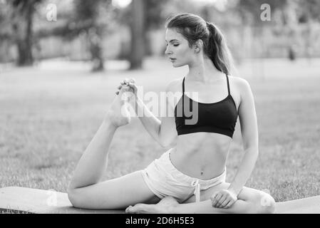 Mädchen, die Yoga im Park während des Tages. Schwarzweiß-Foto. SW Stockfoto