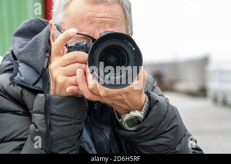 Nahaufnahme eines Mannes mittleren Alters, Mitte 50, der fotografiert. Heller und verschwommener Hintergrund Stockfoto