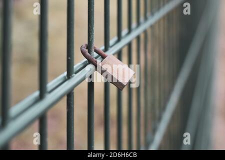 Ein abschließtes Vorhängeschloss hängt an einem Zaun Stockfoto