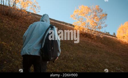 Hippie-Kletterer mit seinem Rucksack hinter ihm Klettern einen steilen Hang in den Wald, Natur und Lifestyle-Konzept Stockfoto