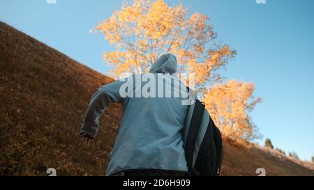 Hippie-Kletterer mit seinem Rucksack hinter ihm Klettern einen steilen Hang in den Wald, Natur und Lifestyle-Konzept Stockfoto