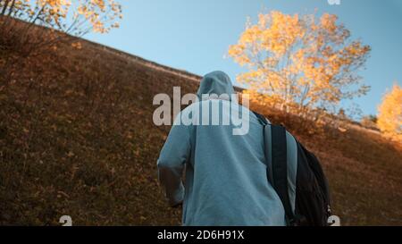 Hippie-Kletterer mit seinem Rucksack hinter ihm Klettern einen steilen Hang in den Wald, Natur und Lifestyle-Konzept Stockfoto