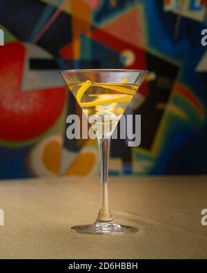 Wodka-Martini-Cocktail mit Zitrone auf goldenem Tuch vor Kandinsky-Kunstwerken Stockfoto