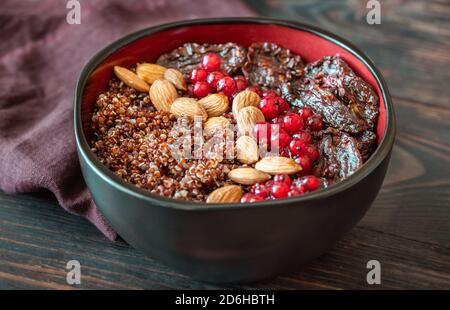 Schüssel mit roten Quinoa mit Oliven, getrockneten Tomaten, Beeren und Nüssen Stockfoto