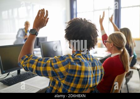 Studierende heben die Hände, um die Frage während der Vorlesung zu beantworten Im Computer-Klassenzimmer der Universität Stockfoto