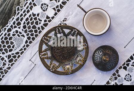 Türkische Kaffeetassen mit einem Glas Wasser auf einem Holztisch mit einem weißen Tuch von oben fotografiert Stockfoto