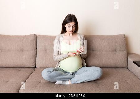 Schwangere Frau mit Pillen in der Hand, Gesundheitskonzept, Medizin während der Schwangerschaft. Stockfoto