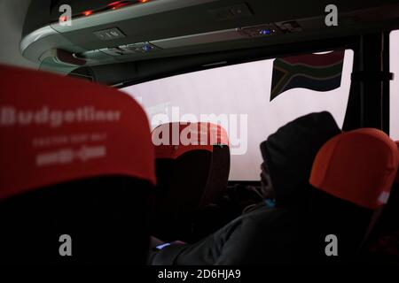 Passagiere, die während der Pandemie von Covid-19 in Südafrika in einem Bus (Reisebus) maskiert fahren. Stockfoto
