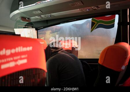 Passagiere, die während der Pandemie von Covid-19 in Südafrika in einem Bus (Reisebus) maskiert fahren. Stockfoto