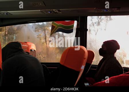 Passagiere, die während der Pandemie von Covid-19 in Südafrika in einem Bus (Reisebus) maskiert fahren. Stockfoto