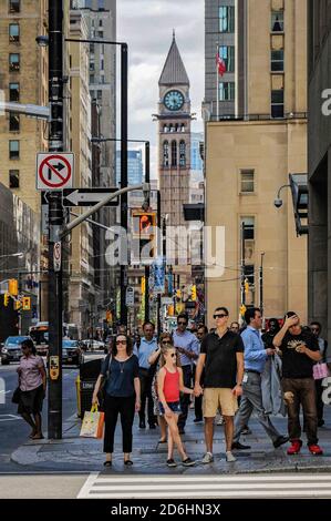 TORONTO, KANADA - 06 28 2016: Menschen warten auf dem Fußgängerüberweg auf der Bay Street in der Innenstadt von Toronto mit Old City Hall Clock Tower im Hintergrund Stockfoto