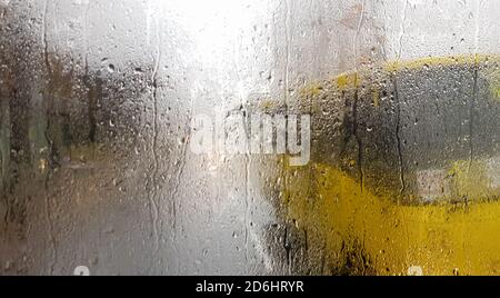 Regen auf die Heckscheibe eines Autos im Herbst. Innenansicht der Straße mit sich bewegenden Autos in der Stadt durch das Fenster aus dem Auto mit Regentropfen. Driv Stockfoto