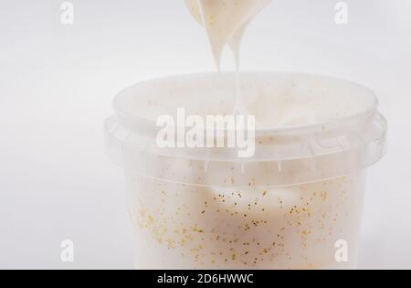 Nahaufnahme von strukturierter beige Creme, die aus einem herausgeschöpft wird Behälter Stockfoto