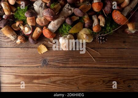 Frische Wildpilze unterschiedlich auf einem hölzernen Hintergrund, Draufsicht, Kopierraum. Herbstkonzept. Stockfoto