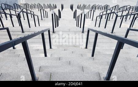 Externe mehrstufige Steintreppe. Es gibt viele Treppen und Geländer aus Metall. Viele Schritte in einer städtischen Umgebung, symbolisch abstrakt zurück Stockfoto