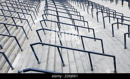 Externe mehrstufige Steintreppe. Es gibt viele Treppen und Geländer aus Metall. Viele Schritte in einer städtischen Umgebung, symbolisch abstrakt zurück Stockfoto