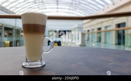 Klassischer Kaffee Latte Macchiato in einer Glastasse auf dem Tisch. Glasbecher mit heißem Getränk Stockfoto