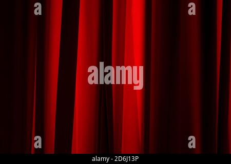 Bukarest, Rumänien - 14. Juli 2020: Die Sonnenstrahlen beleuchten die Falten eines roten Vorhangs. Stockfoto