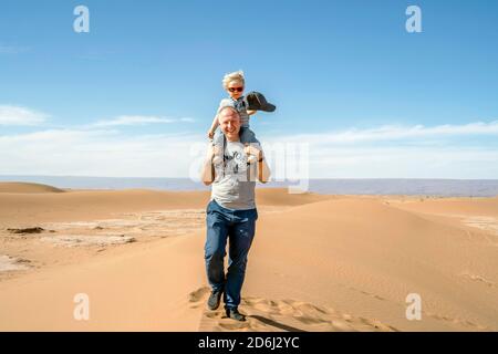 Vater, der mit einem 2-jährigen Sohn durch die Sahara in Marokko, Afrika, geht Stockfoto