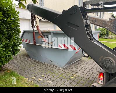 Viersen, Deutschland - Oktober 17. 2020: Blick auf Kran Putting Container für organische Gartenabfälle auf Garageneingang des Privathauses Stockfoto