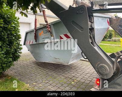 Viersen, Deutschland - Oktober 17. 2020: Blick auf Kran Putting Container für organische Gartenabfälle auf Garageneingang des Privathauses Stockfoto