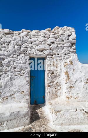 Freiliegende weiß lackierte Steinmauer mit schmaler blau lackierter Eingangstür, Mykonos-Stadt, Mykonos-Insel, Griechenland Stockfoto