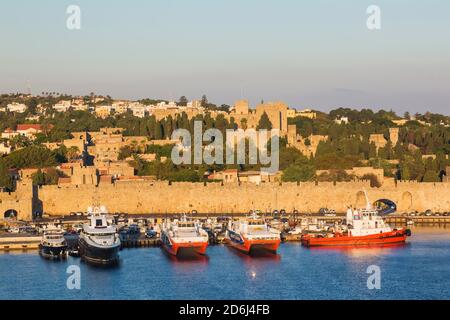 Fährschiffe dockten in Handelshafen und Altstadt von Rhodos mit Befestigungsmauern bei Sonnenaufgang, Rhodos, Griechenland Stockfoto